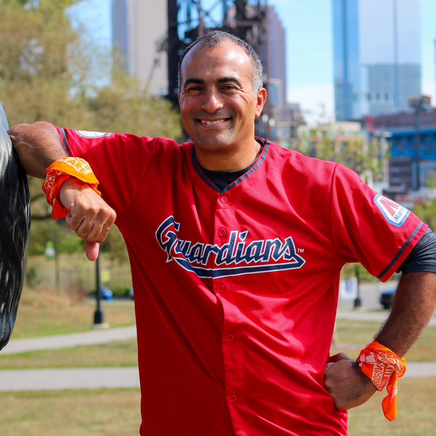 Man wearing a red sports jersey with 'Guardians' logo outdoors.