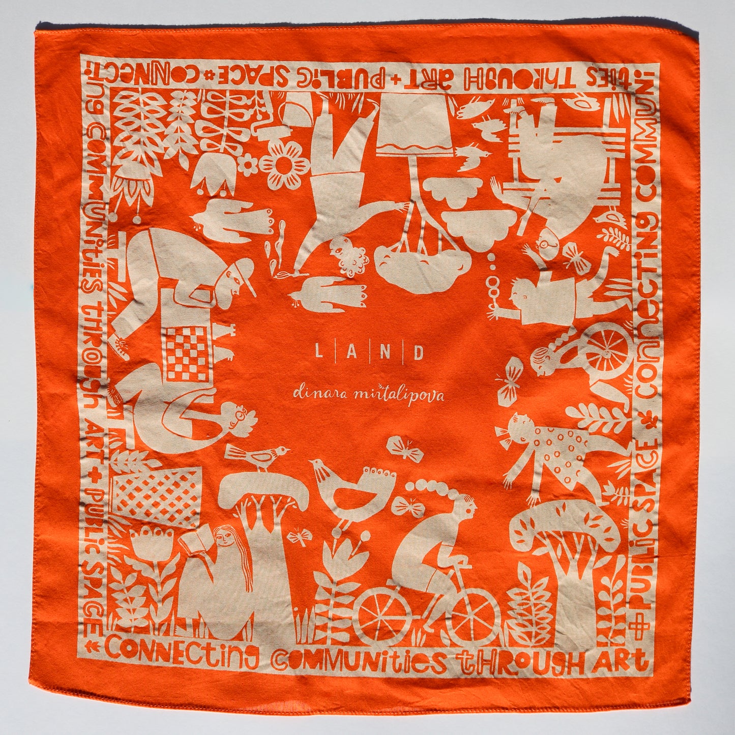 Orange scarf with white artistic designs and text on a gray background