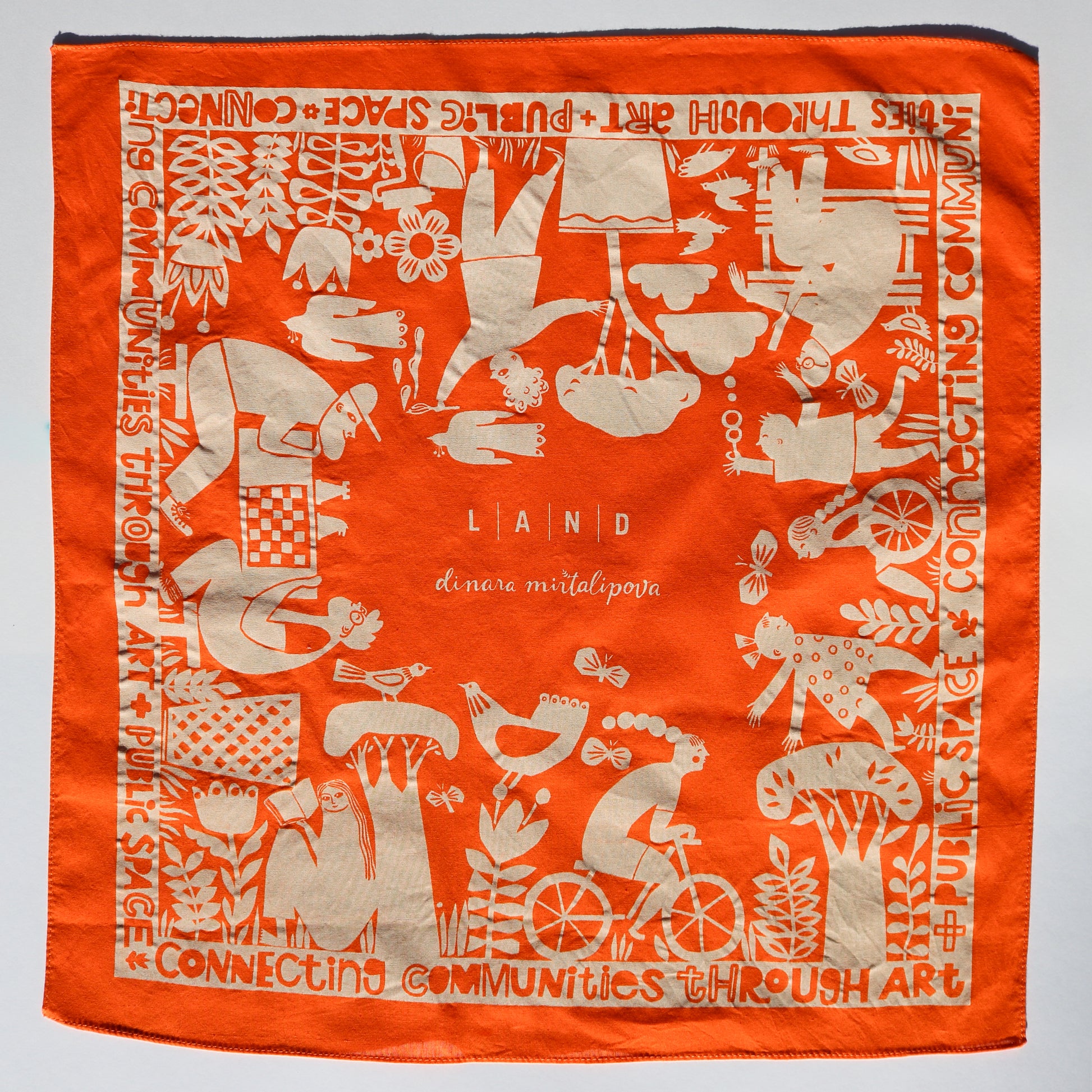 Orange scarf with white artistic designs and text on a gray background